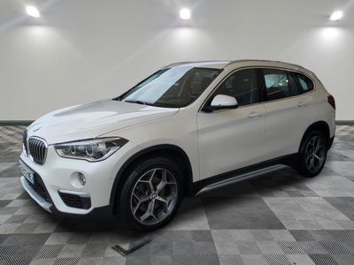 un SUV BMW blanc garé dans un showroom au sol à damier