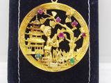 une image représentant un pendentif plaqué or sur lequel figurent un homme et une femme dans un paysage
