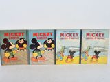 three mickey mouse books are lined up on a white surface