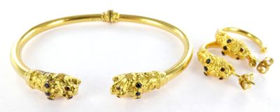 a close up of a gold bracelet and ring on a white surface