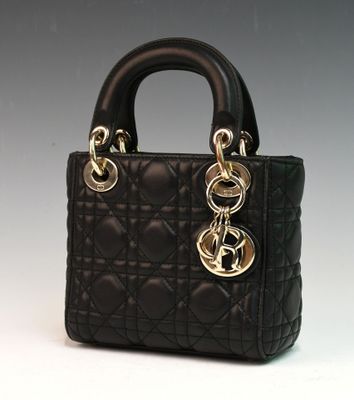 sac à main noir matelassé avec des finitions dorées sur fond blanc