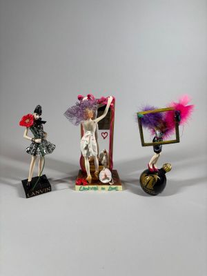 trois figurines représentant une femme en robe et un homme en costume
