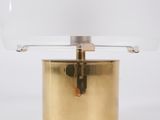 a gold table lamp with a clear glass shade on top of it