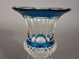 un vase en verre bleu avec un socle transparent posé sur une table