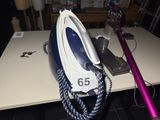 a blue and white iron sitting on a table next to a pink cord