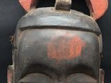 a black mask with a red face on a black background