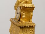 a gold clock sitting on top of a wooden table
