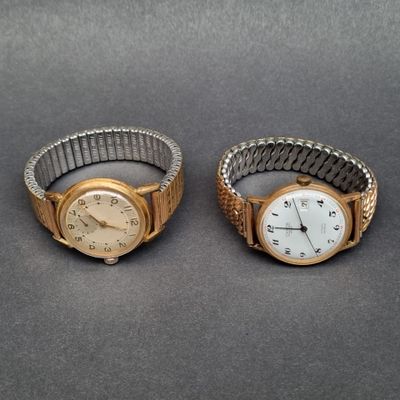 une paire de montres-bracelets pour femmes posées sur une table, sur fond gris