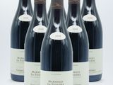 six bottles of wine are lined up in a row on a white surface