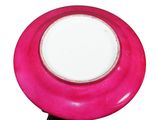 a pink plate with a white center on a black stand