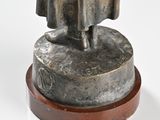 statue of a man with a hat and cloak on a wooden base