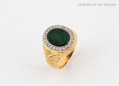 une image d'une bague en or avec une pierre verte entourée de diamants