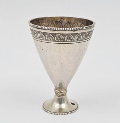 un gobelet ancien en argent posé sur une surface blanche, sur fond blanc