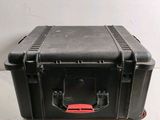une valise noire avec une poignée rouge posée par terre