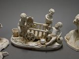 three figurines of people sitting on a bench