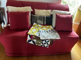 a red couch with many pillows on it in a living room