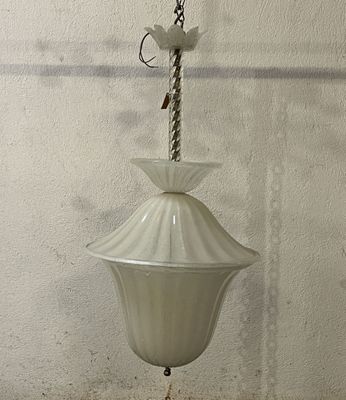a white lamp hanging from a chain on a wall