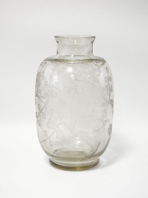 un vase en verre transparent posé sur une surface blanche, avec un fond blanc