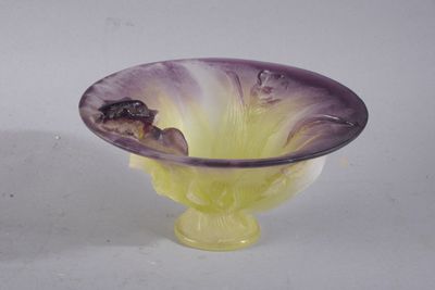 un saladier en verre violet et jaune posé sur une table blanche