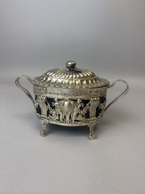 une casserole ancienne en métal argenté, ornée de motifs noirs et blancs