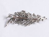 a silver brooch that has a leaf design on it