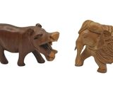 two wooden elephants standing next to each other on a white surface