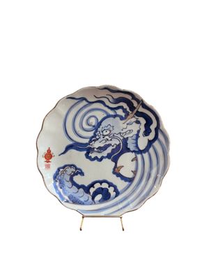 assiette bleue et blanche ornée d'un dragon, posée sur un socle