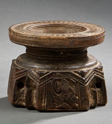 un vieil objet en bois orné de sculptures sur une surface grise