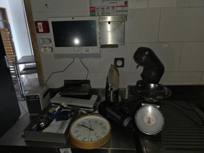 une photo d'un plan de travail de cuisine encombré, sur lequel se trouvent une horloge et un micro-ondes