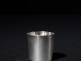 a small silver cup sitting on a black surface