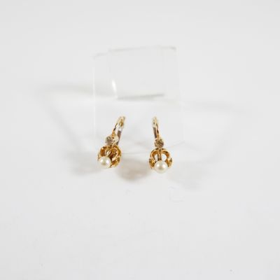 une paire de boucles d'oreilles en or sur une surface blanche