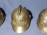 trois casques de pompier en laiton vieilli sur fond bleu