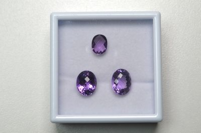 trois améthystes violettes dans une boîte blanche posée sur une table