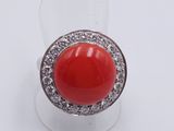 an image of a red coral and diamond ring on a clear ring holder