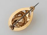 an 18k gold broochle depicting a bird and a sword
