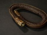 a brown leather bracelet with a brass clasp on a black surface