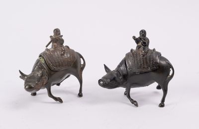 pair of bronze figurines of a man riding a boar and a man riding a pig