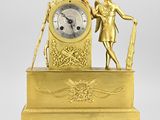 une image représentant une horloge en or surmontée d'une statue