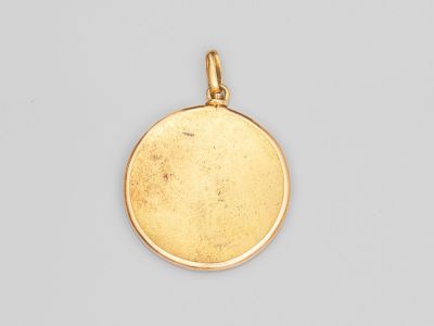 un pendentif plaqué or présentant un motif rond sur fond blanc