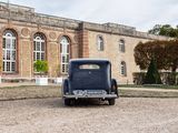 an old car parked in front of a large building