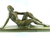 bronze statue of a woman laying on her stomach on a marble base