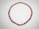 un gros plan d'un collier rouge et or posé sur une surface blanche