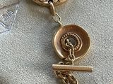an image of a close up of a gold necklace with a bird on it