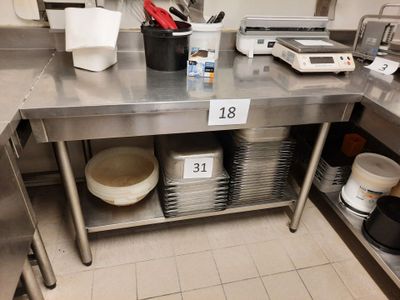 une table en acier inoxydable sur laquelle sont posées de nombreuses assiettes et casseroles