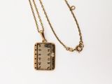 a close up of a gold necklace with a clock on it