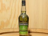 une bouteille de Chartreuse posée sur un tonneau