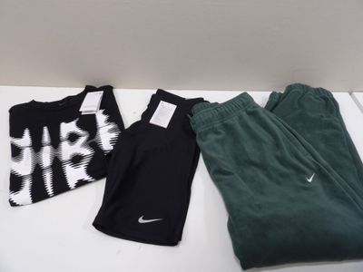 Trois paires de pantalons Nike et un t-shirt sont posés sur une table