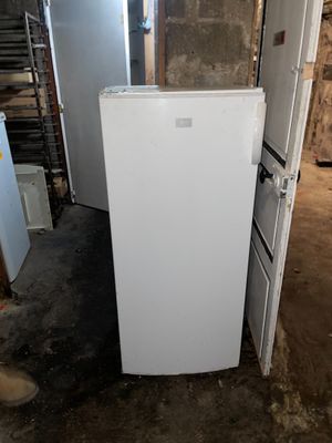 un réfrigérateur blanc dans une pièce sale, dont la porte est ouverte