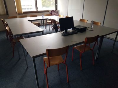tables and chairs in an empty room with a laptop on the table