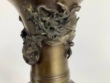 a bronze vase that has a face on it
